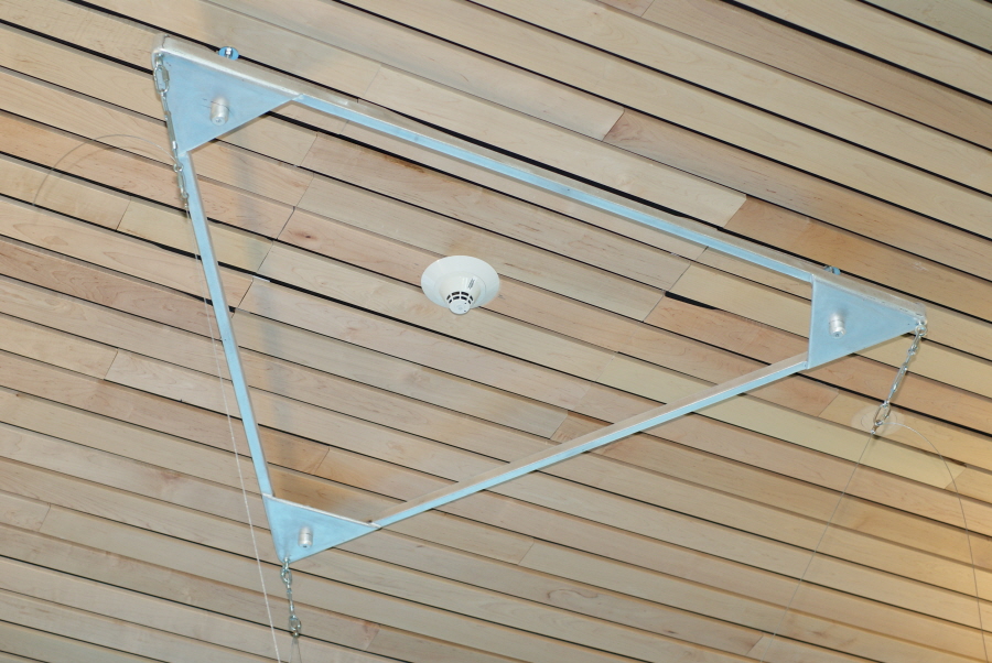A solid metal frame in the shape of an equilateral triangle is mounted into the ceiling around a smoke detector. Science On a Sphere is attached by wires to the corners of the triangular frame