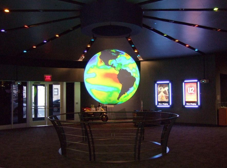 Science On a Sphere hangs in the center of an empty lobby displaying a colorful ocean dataset