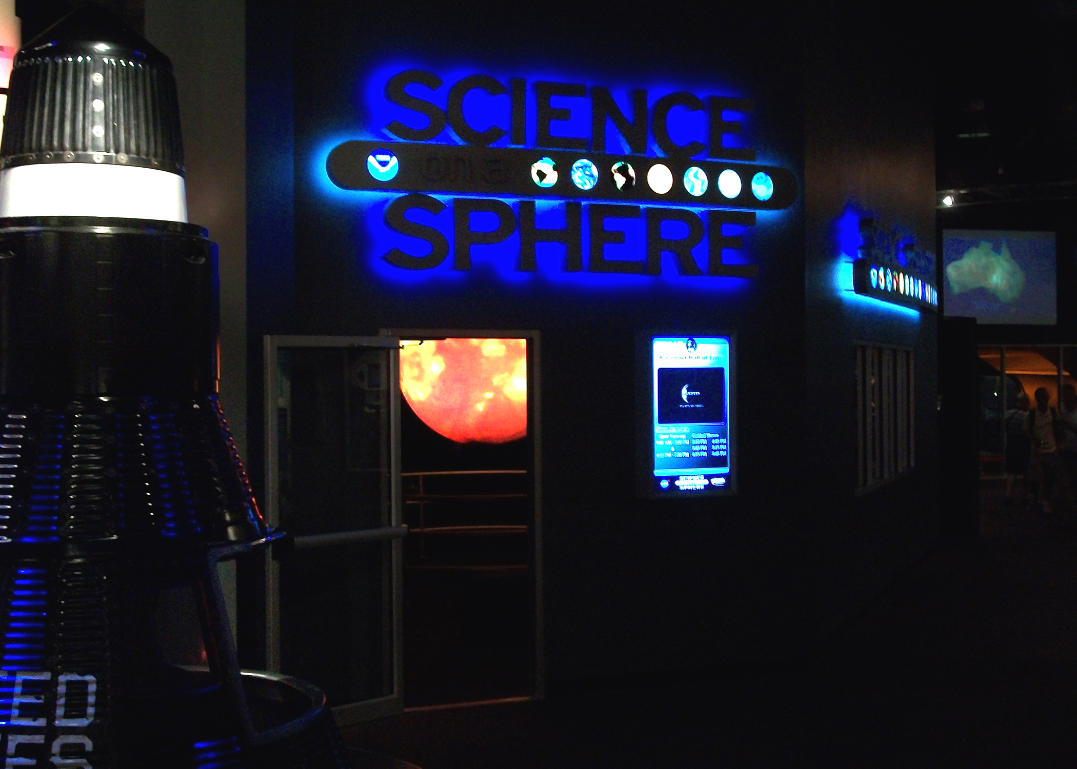 Science On a Sphere is just visible through an open door to a darkened theater. It displays imagery of the Sun