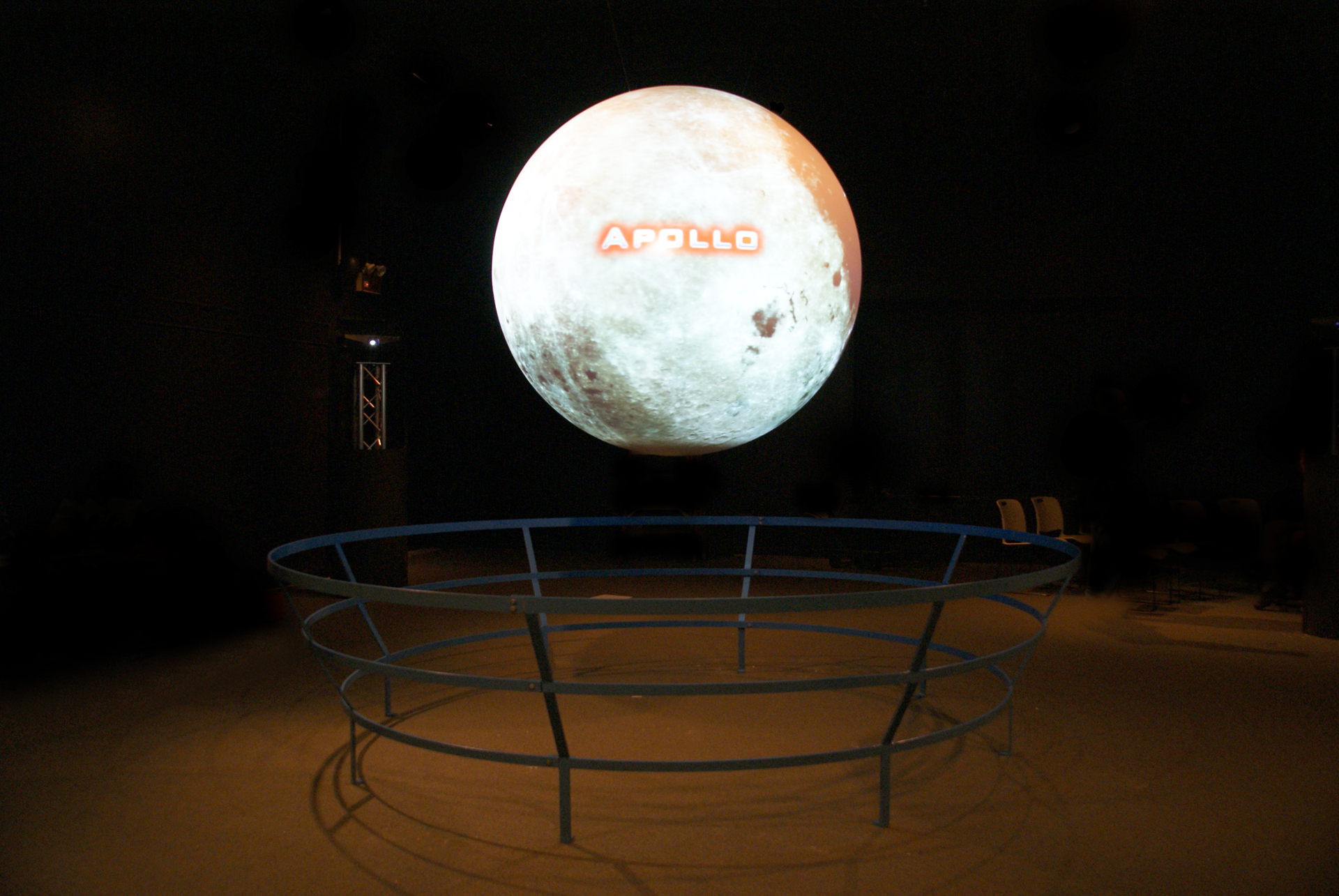 Science On a Sphere hangs in an empty room, the word 'Apollo' is visible on the Sphere