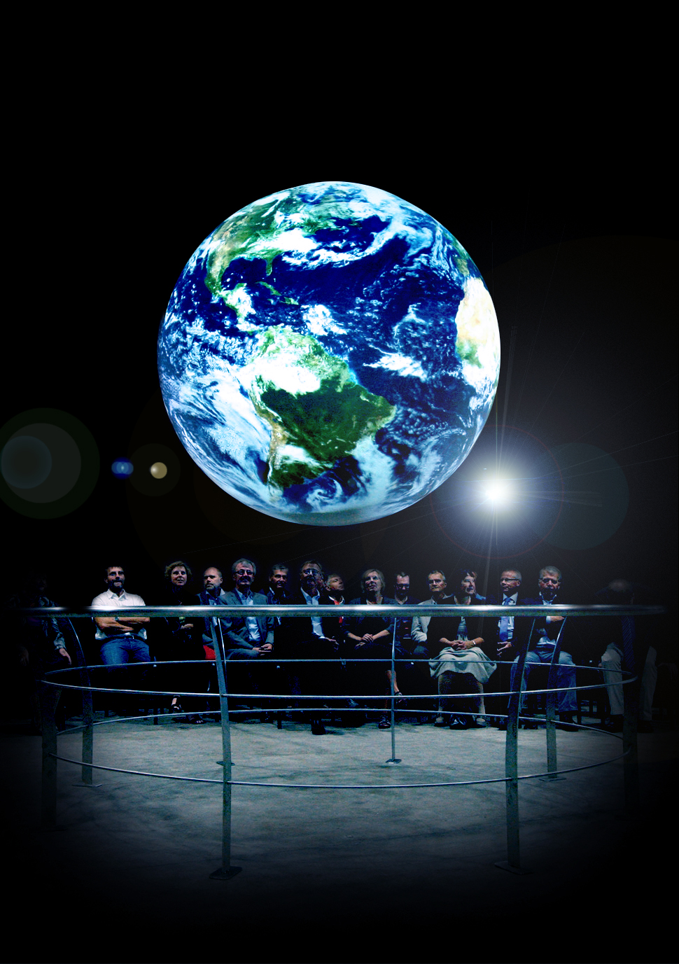 A group of people sit in two rows watching Science On a Sphere