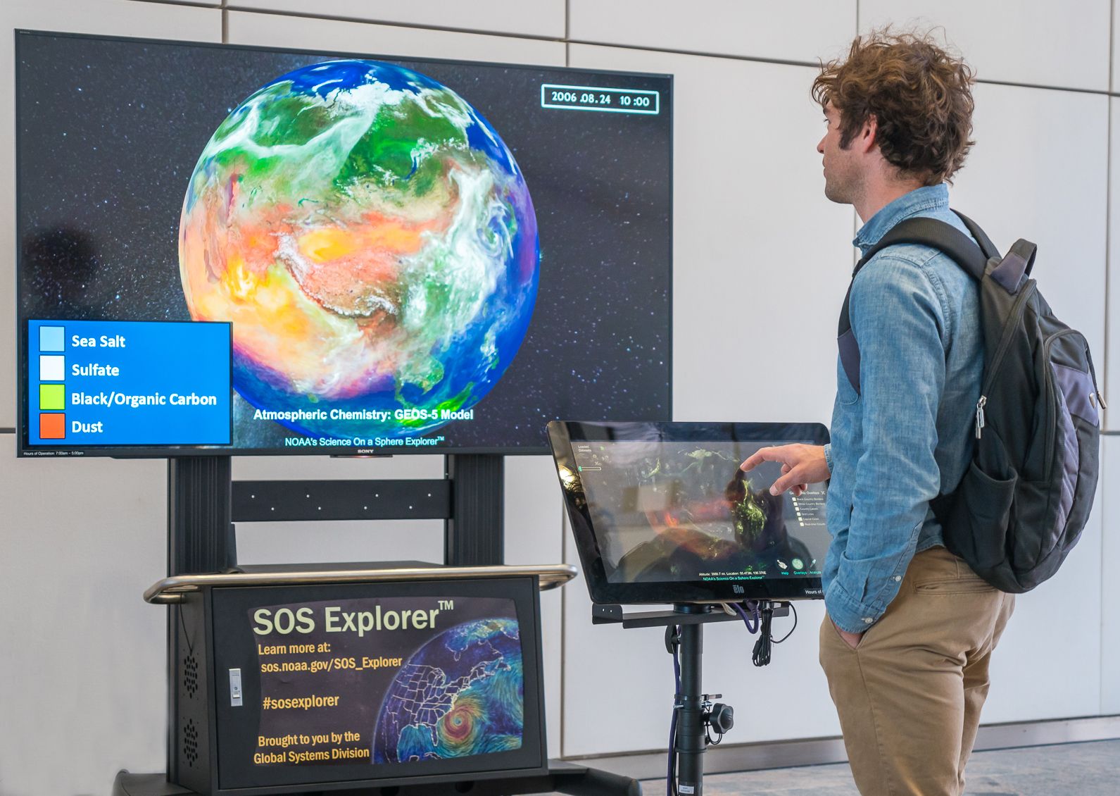 A person touches a smaller screen and controls a larger screen displaying
     atmospheric chemistry on SOS Explorer.