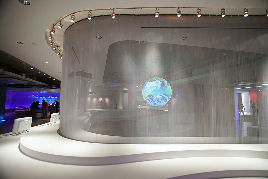 Science On a Sphere is visible through a sheer curtain, enclosed in a space created by a long, white, curving table