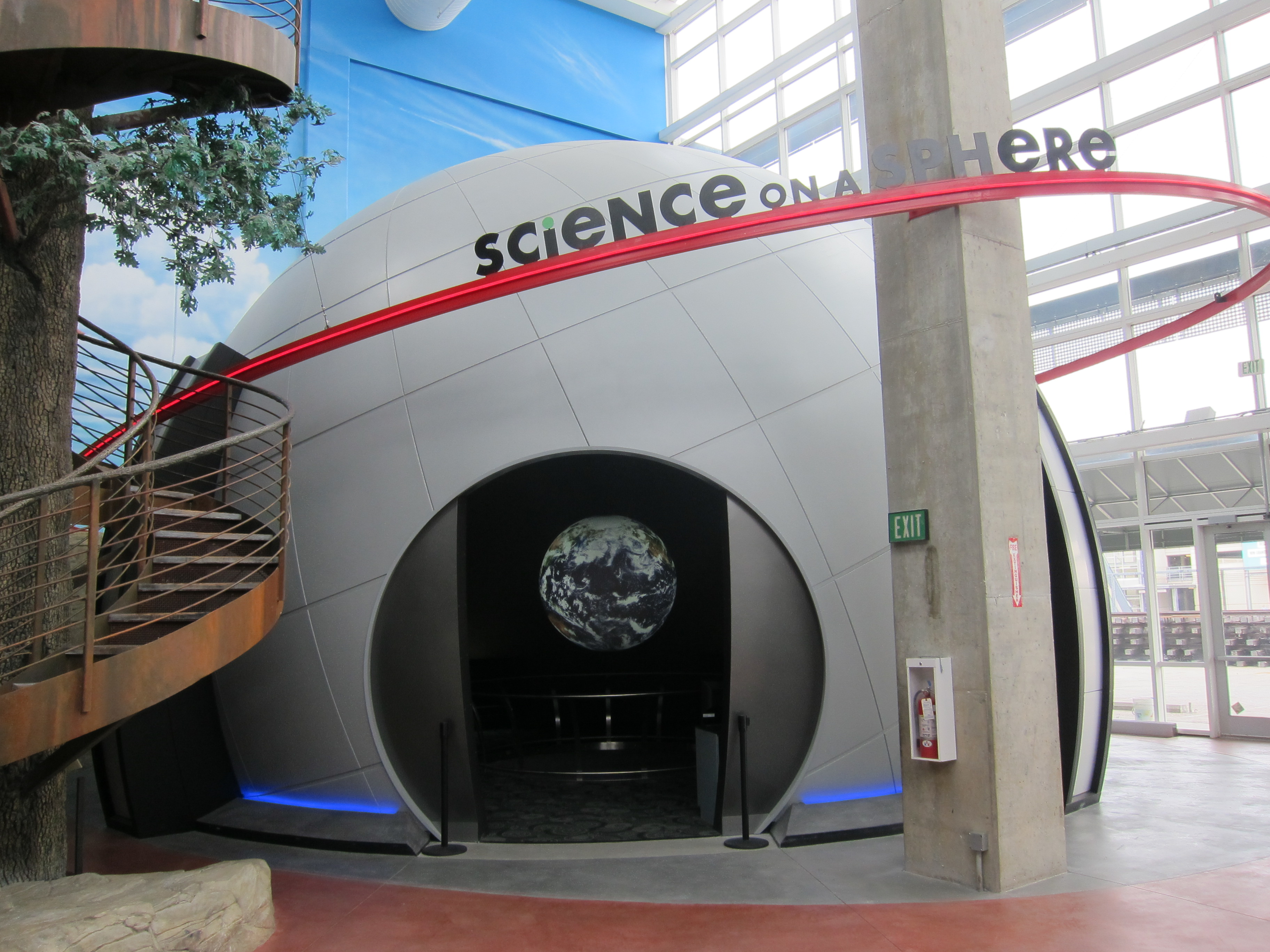 Science On a Sphere is visible through the entry to a small dome inside a larger exhibit hall